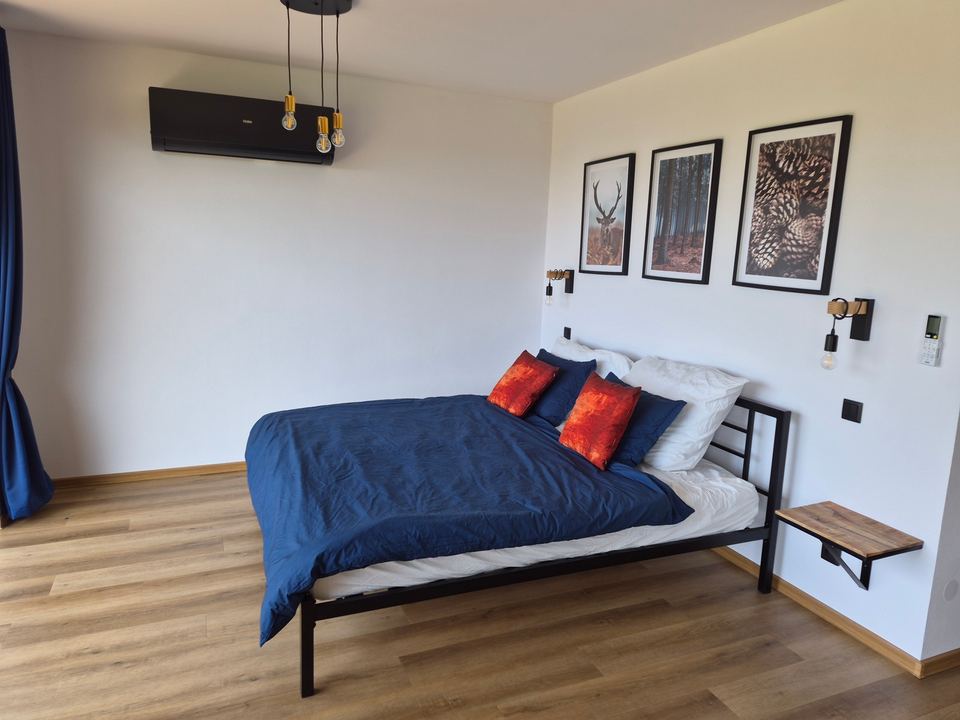 Manželská postel 180 × 200 cm s modrým povlečením a nástěnnými lampičkami